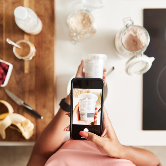Woman Wearing Fitness Clothing Scanning Qr Code On Food Packaging To Find Nutritional Information