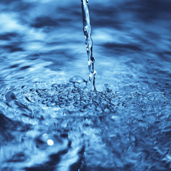 close up of water falling on transparent water surface